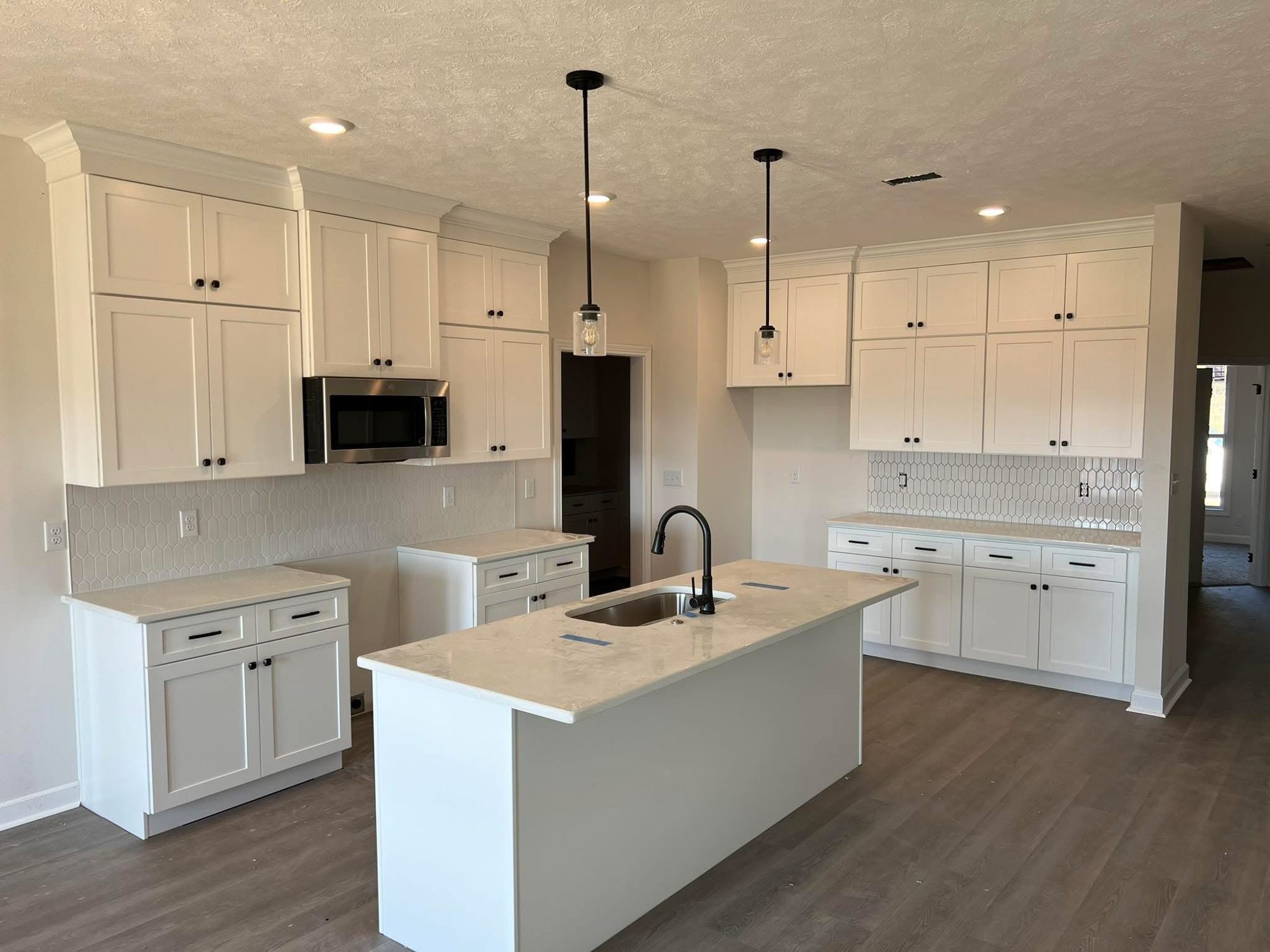 Finished white shaker kitchen with center island, quartz countertops, and pendant lighting by Middle Tennessee Cabinetry