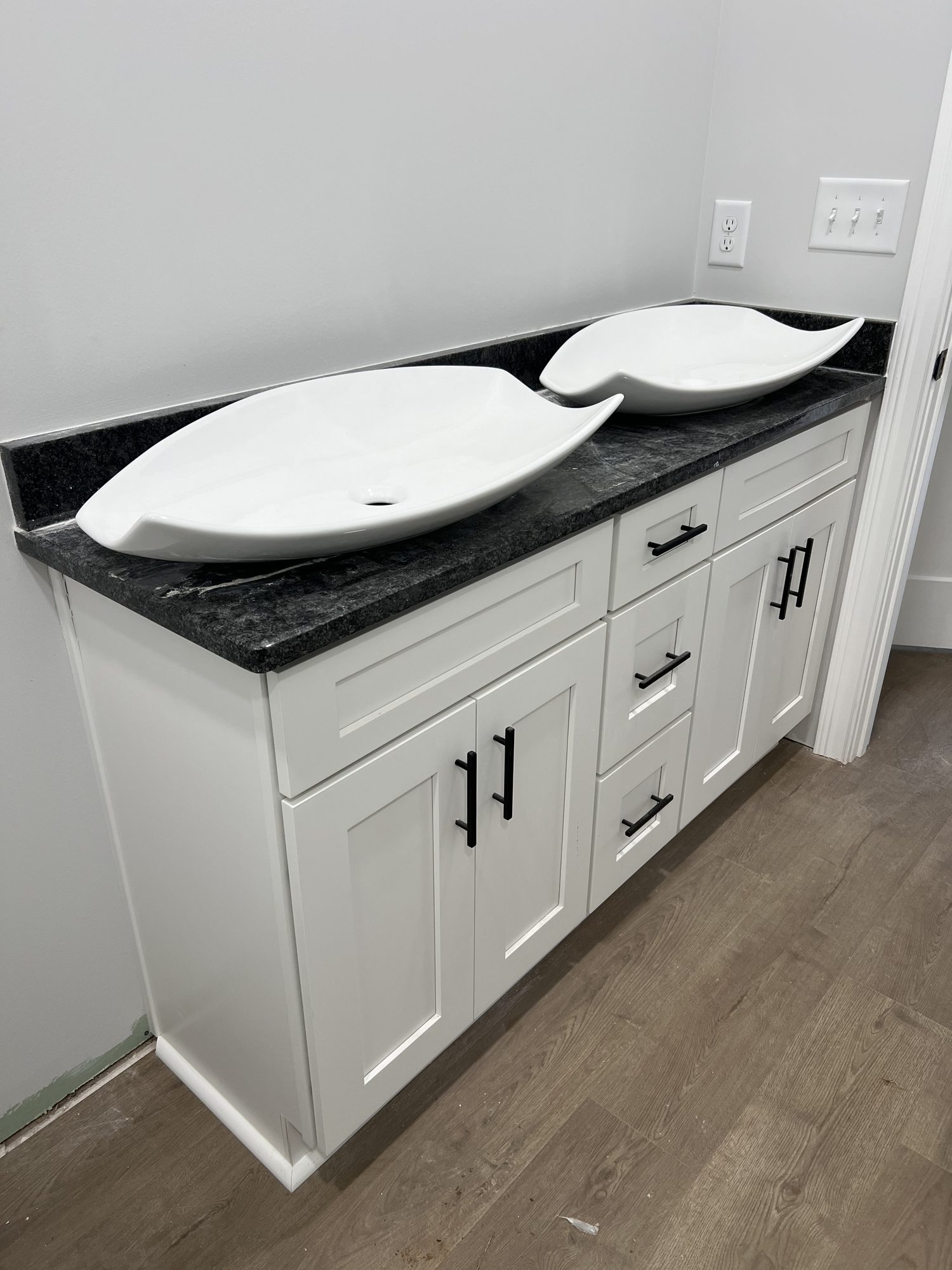 Bathroom vanity with dual vessel sinks and black countertop
