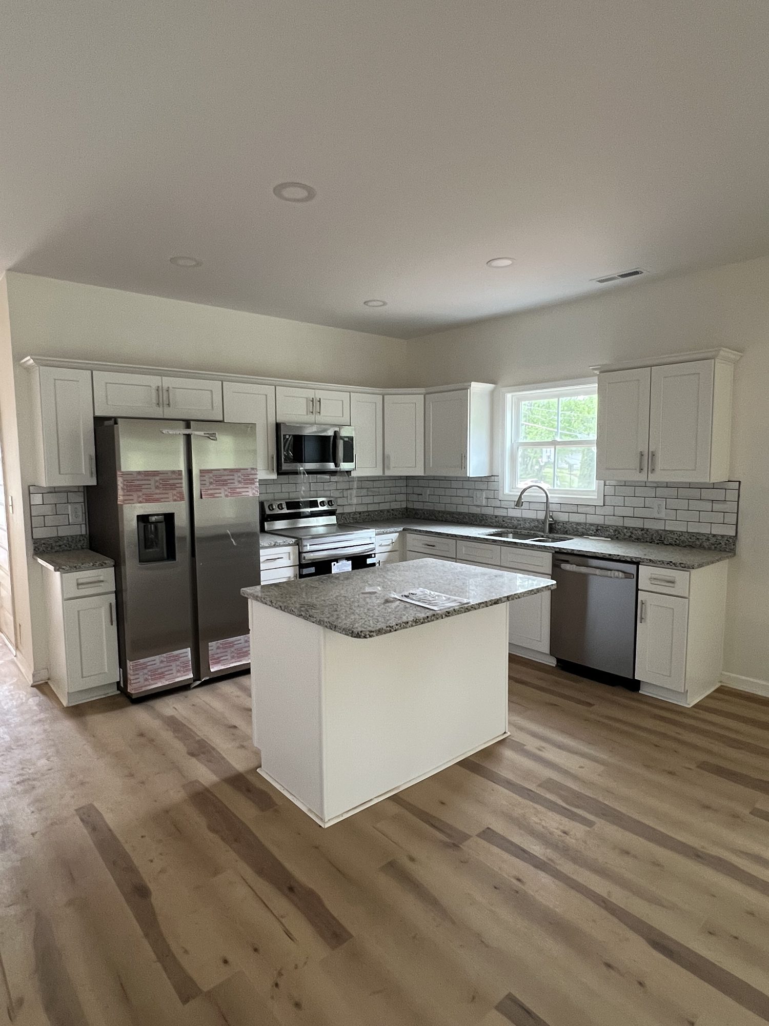 Finished white kitchen with center island and granite countertops